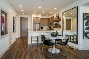 A modern kitchen with wooden cabinets, a stainless steel refrigerator, and a white island with bar stools.