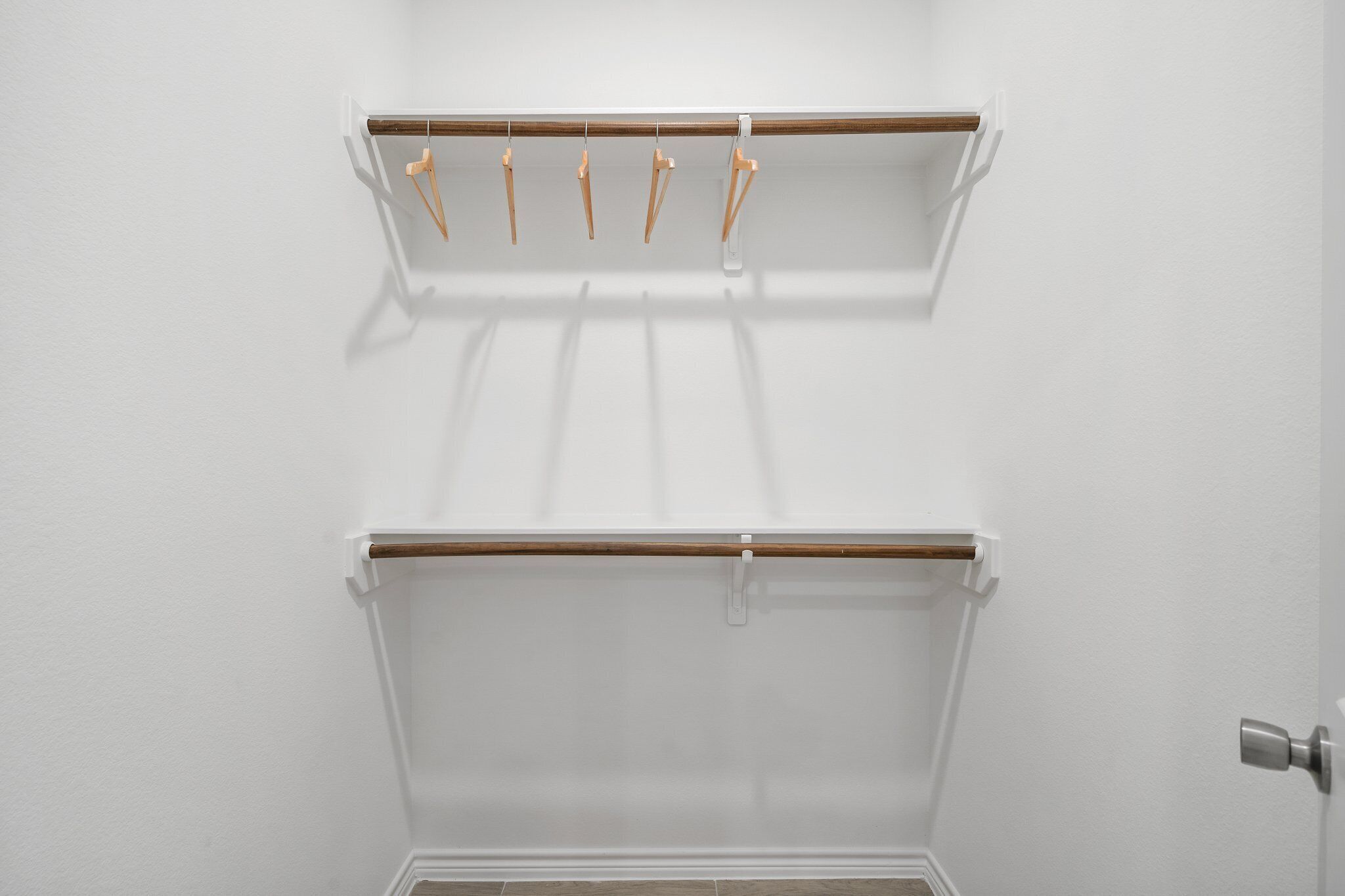 A white room with a wooden shelf and a whiteboard on the wall.