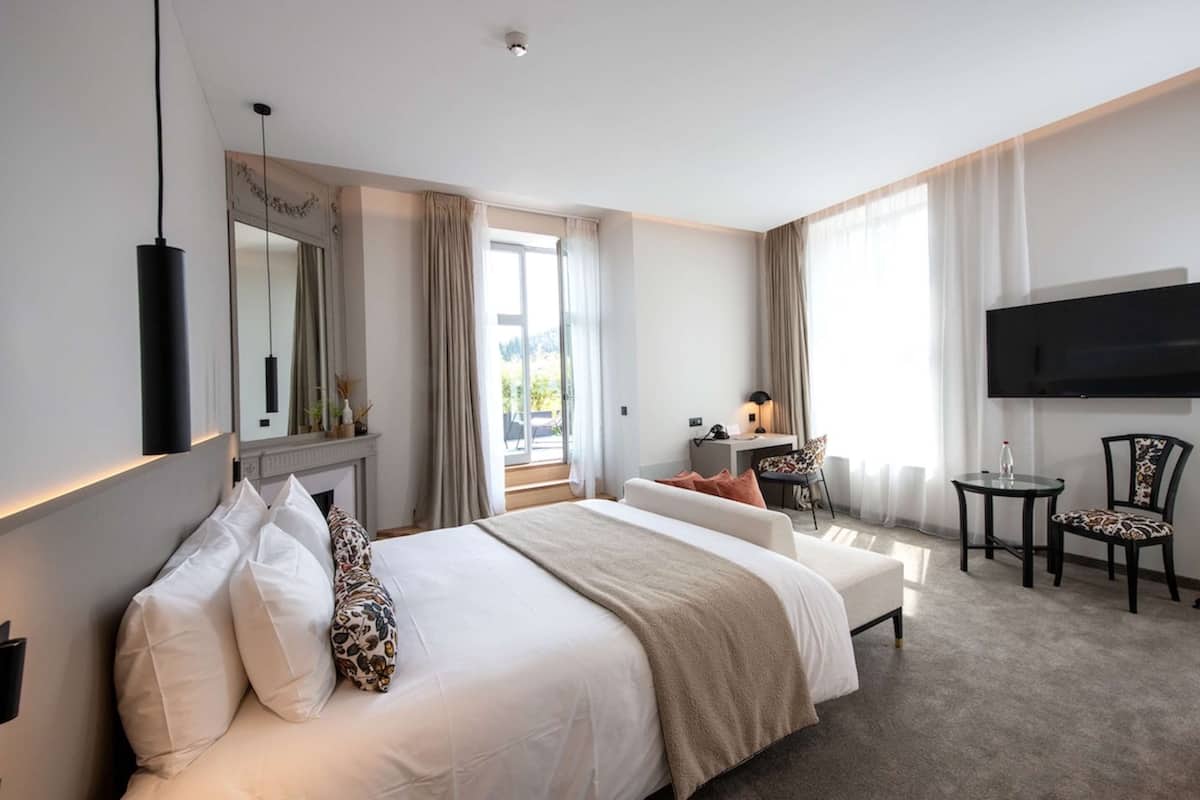 Habitación de hotel con una cama grande, un escritorio, una silla, un televisor y una chimenea.