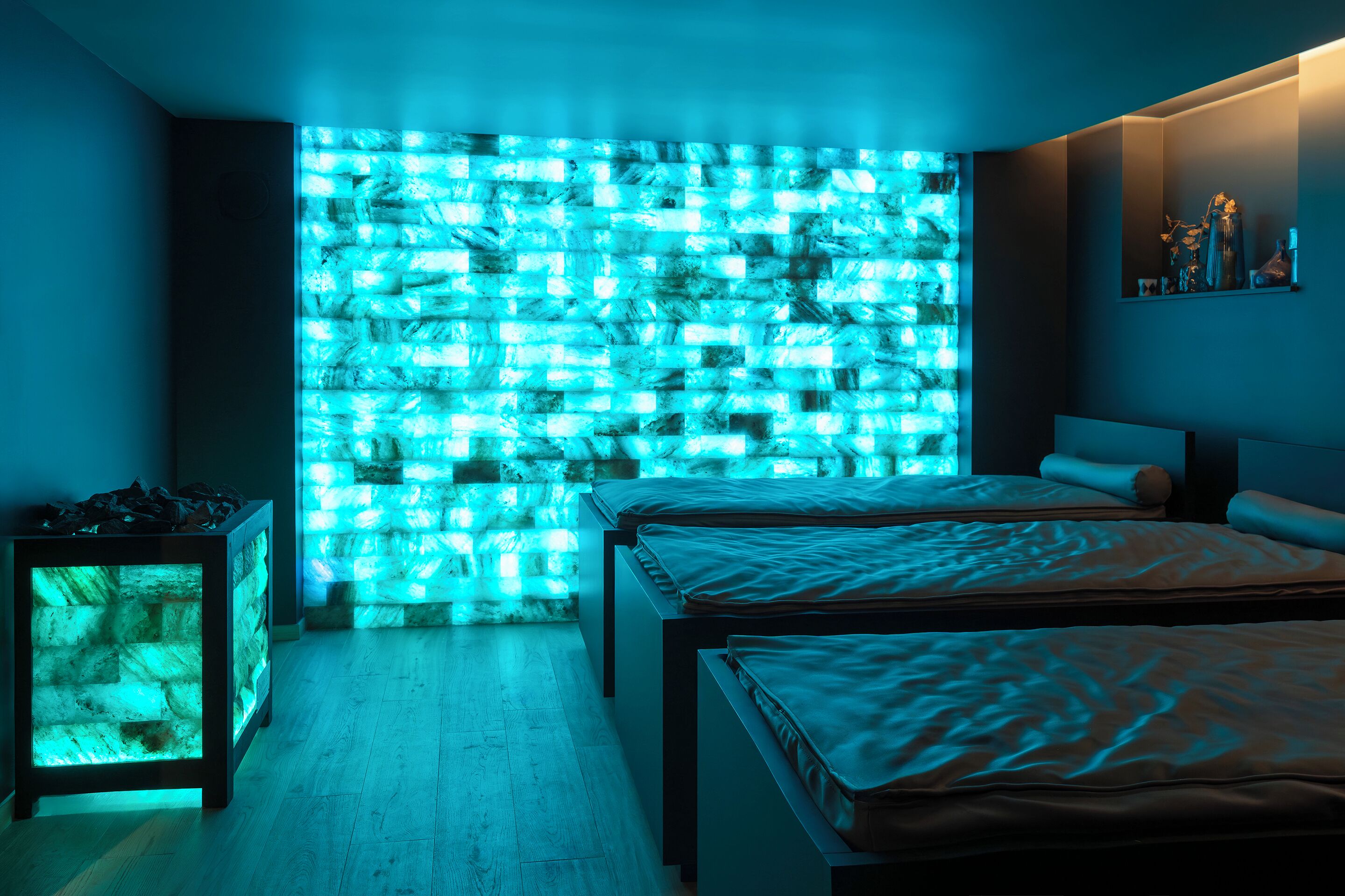 A modern bedroom with two beds, a wall-mounted shelf, and a unique illuminated wall feature.