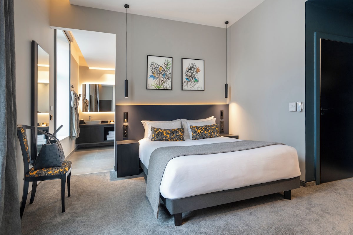 Un dormitorio moderno con una cama grande, una silla, un escritorio y un espejo.