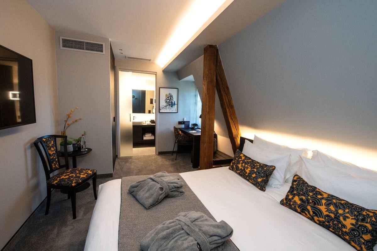 Habitación de hotel con una cama grande, dos mesitas de noche, una silla, un escritorio y un espejo.