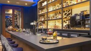 Zona de bar con una barra larga, estantes con botellas de licor y equipo de bar.