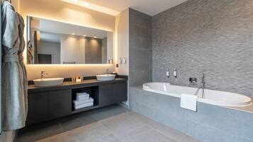 A modern bathroom with a large mirror, two sinks, a bathtub, and a towel rack.