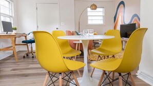 Uma zona de refeições moderna com uma mesa redonda branca, cadeiras amarelas e decoração minimalista.