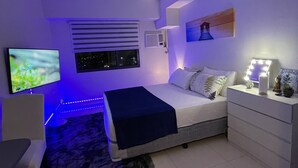 A modern bedroom with a bed, bedside table, lamp, and a TV.