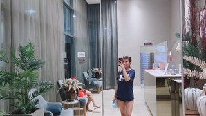 A modern hotel lobby with a seating area, a reception desk, and a large mirror reflecting the space.
