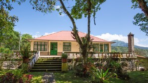 A two-story building with a red roof, a green door, and a stone staircase leading to the entrance. - Niebli Historical Farm and Lodge at Pululahua Volcano (Calacali)