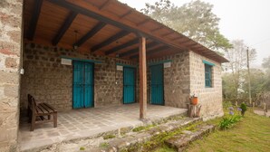 A stone building with a wooden porch, blue doors, and a bench. - Niebli Historical Farm and Lodge at Pululahua Volcano (Calacali)