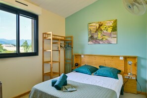 Una camera da letto con un letto, una testiera in legno, una finestra, un quadro e una ventola.