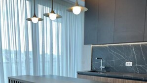 Une cuisine moderne dotée d’un plan de travail en marbre, de meubles en bois et de luminaires suspendus.