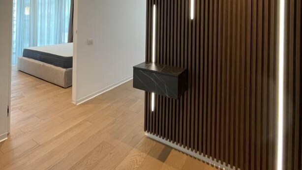 Une pièce moderne avec un mur en lambris de bois, un banc intégré et une petite étagère noire.