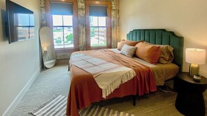 A bedroom with a bed, a ceiling fan, a window, and a nightstand. - Downtown Luxury Condo for 2! (San Antonio)
