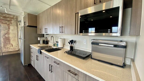 A modern kitchen with stainless steel appliances, wooden cabinets, and a granite countertop. - Downtown Luxury Condo for 2! (San Antonio)