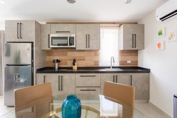 A modern kitchen with a refrigerator, microwave, and wooden backsplash. - Emerald 1BR APT -#E1 in Noord-Sleeps 2 (Noord)