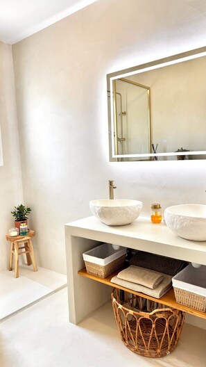 Ein modernes Badezimmer mit zwei Waschbecken, einem großen Spiegel und einem Korbwannen unter der Ablagefläche.