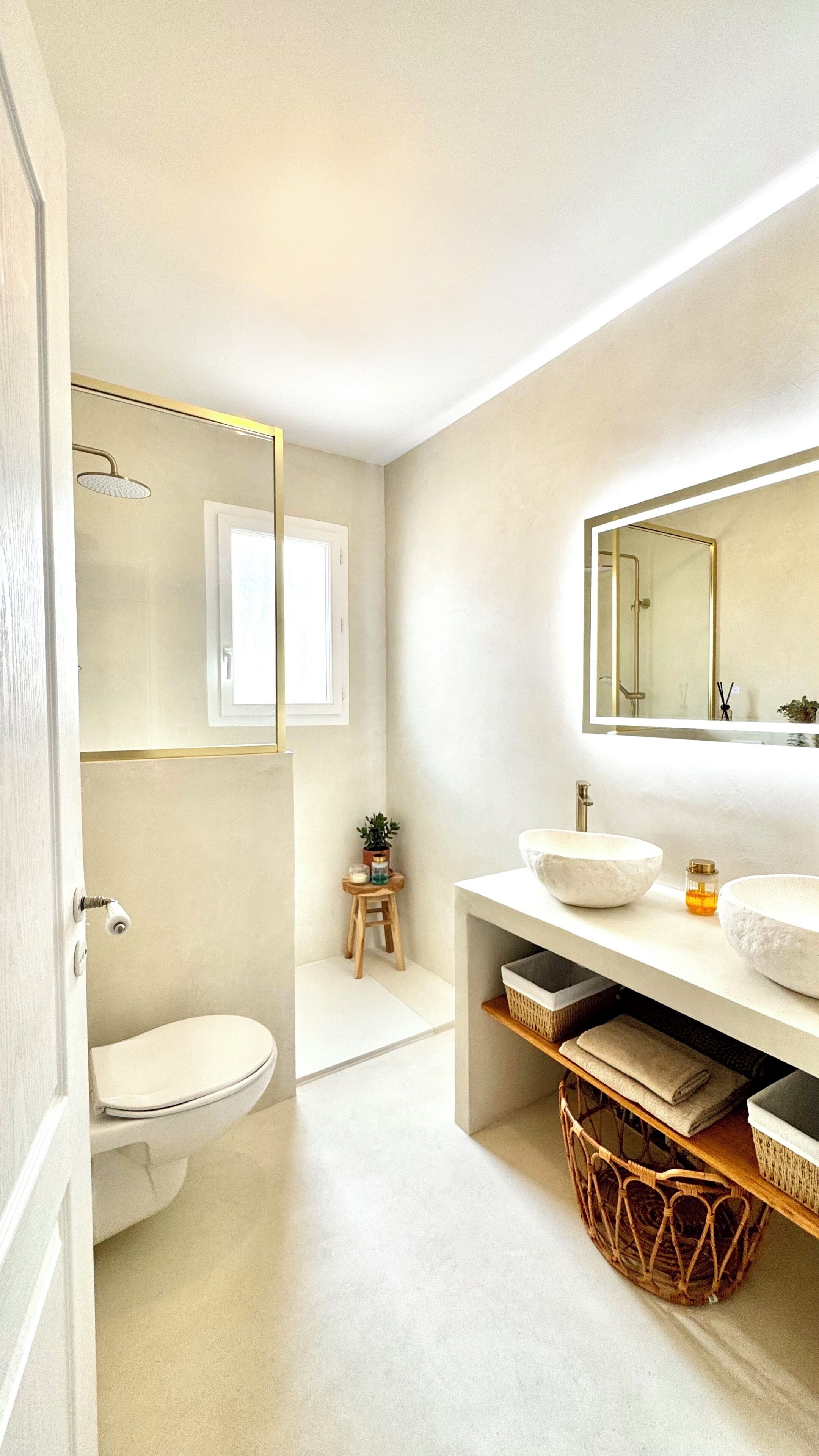 Een moderne badkamer met toilet, wastafel, spiegel en douche.