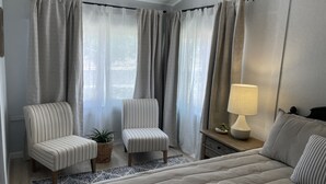Een slaapkamer met een bed, twee stoelen, een lamp en een plant.
