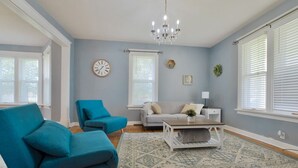 A living room with a blue sofa, a grey sofa, a coffee table, and a chandelier. - Nauvoo Family Home 15 Minutes From Temple (Hamilton)