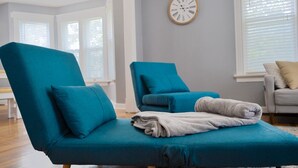 A modern living room with teal armchairs, a grey sofa, and a large wall clock. - Nauvoo Family Home 15 Minutes From Temple (Hamilton)