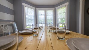 A dining area with a wooden table set for six, large windows with blinds, and a view of greenery outside. - Nauvoo Family Home 15 Minutes From Temple (Hamilton)