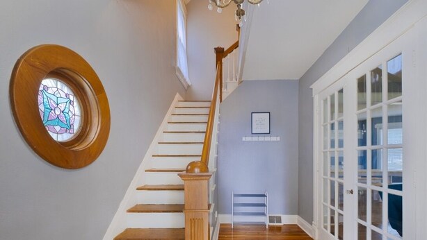 A staircase with wooden steps and a wooden handrail, leading to a room with a large window and a door with glass panels. - Nauvoo Family Home 15 Minutes From Temple (Hamilton)