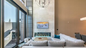 Un salon moderne avec une cheminée, un grand canapé et un coin repas.
