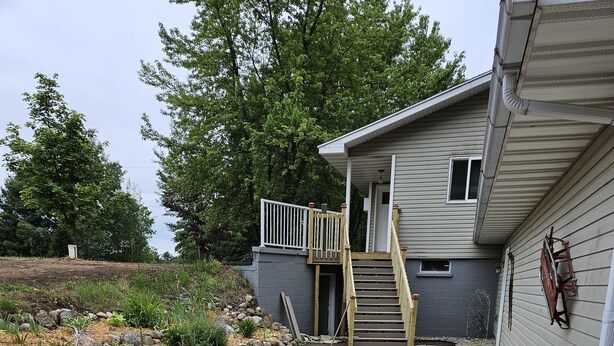 Un chemin de pierres menant à une maison dotée d’un escalier en bois et d’une petite terrasse.