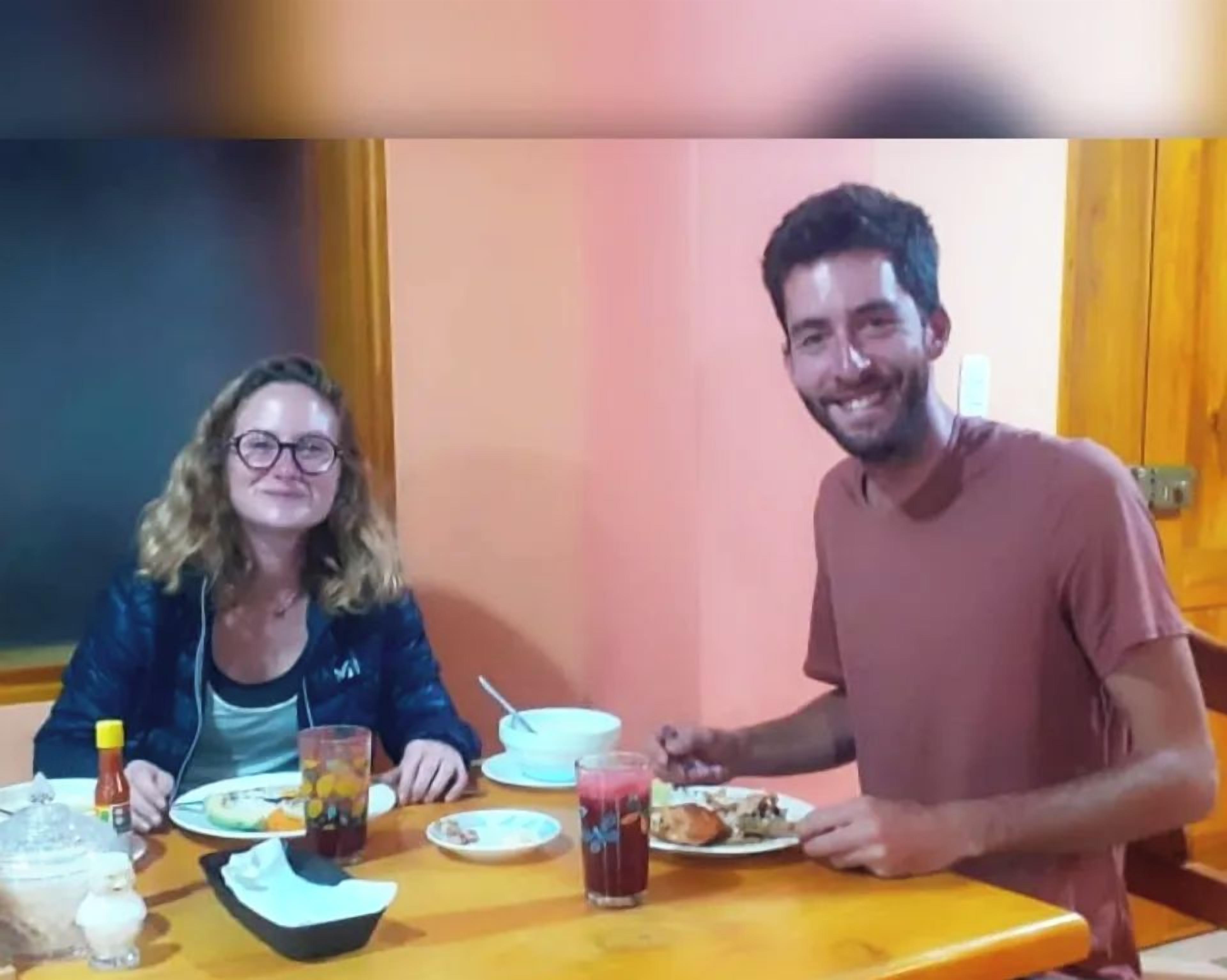 Una mesa de comedor con platos de comida, un vaso de jugo y aderezos.