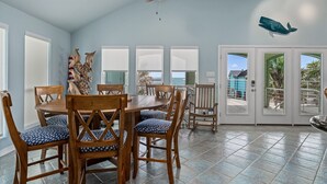 A dining area with a wooden table and chairs, a ceiling fan, and a view through the glass doors.