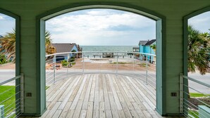 A wooden deck with a view of the beach and ocean.