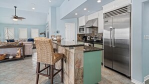 A modern kitchen with a large island, stainless steel appliances, and a seating area with a sofa and chairs.