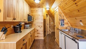 Una cocina compacta con paredes de madera, estufa integrada y un lavabo.