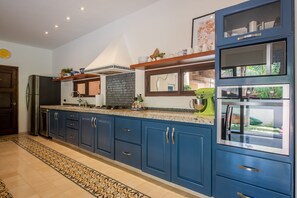 A modern kitchen with blue cabinets, a stainless steel refrigerator, and a built-in oven. - Spacious Private Villa with Pool Backing to Golf Course Beach Only Minutes Away (Puerto Aventuras)