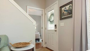 A hallway with a white door, a framed picture, and a wicker basket on a small table. - *10 Minutes to Downtown & Biltmore, Next to Parkway (Asheville)