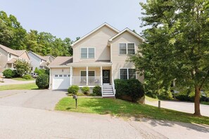 A two-story residential house with a front porch, a garage, and a well-maintained lawn.