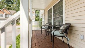 A covered porch with a table and chairs, a large window, and a white railing. - *10 Minutes to Downtown & Biltmore, Next to Parkway (Asheville)
