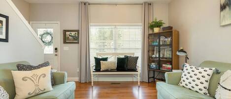 A living room with two light green sofas, a wooden bench, and a bookshelf.