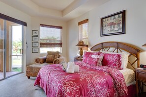 Quarto com cama grande, cadeira, mesa de cabeceira e um quadro na parede.