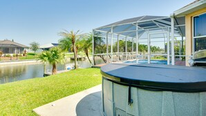 A covered outdoor area with a pool, palm trees, and a view of a body of water. - Near Sand & Sun, Cape Coral Home w/ Private Pool (Cape Coral)