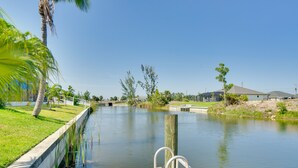 A calm waterway with a wooden dock and a concrete walkway on the left. - Near Sand & Sun, Cape Coral Home w/ Private Pool (Cape Coral)