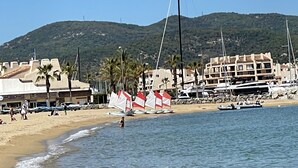 A beach with sailboats, a sandy shore, and buildings in the background.