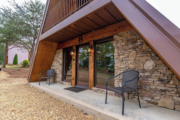 A building with a stone facade, a wooden balcony, and two chairs outside.