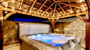 A hot tub with a stone wall backdrop and wooden beams overhead. - Modern 3-Bedroom Villa with Jacuzzi and Gym (Las Cruces)