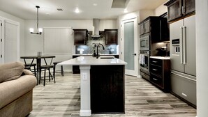 A modern kitchen with a central island, dark cabinetry, and stainless steel appliances. - Modern 3-Bedroom Villa with Jacuzzi and Gym (Las Cruces)