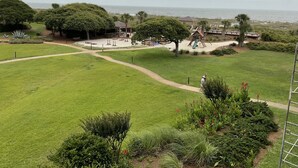 Een park met een speeltuin, picknicktafels en uitzicht op de oceaan.