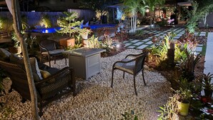A well-lit outdoor patio area with seating, a small pool, and various potted plants. - Mid Century Spacious House 4BR/Heated pool (Oakland Park)