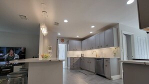 A modern kitchen with grey cabinets, a central island, and a bar area. - Mid Century Spacious House 4BR/Heated pool (Oakland Park)