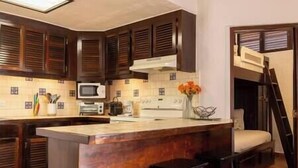 A kitchen with dark wooden cabinets, a central island with stools, a microwave, and a toaster. - Cozy Golf Course View Villa inside the Wyndham Grand Rio Mar Resort (Rio Grande)