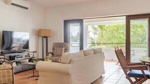 A living room with a sofa, TV, and a dining area with chairs. - Cozy Golf Course View Villa inside the Wyndham Grand Rio Mar Resort (Rio Grande)